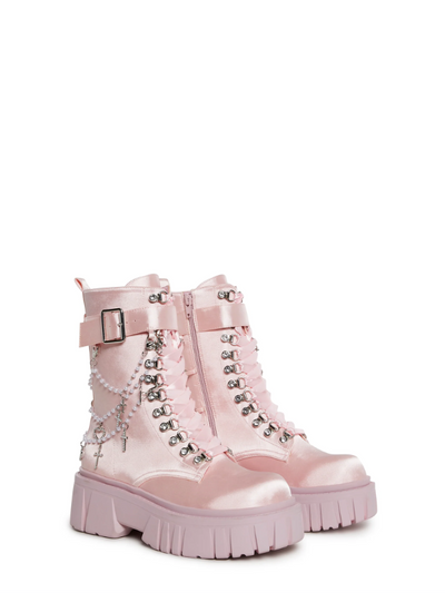Angelcore Mayhem Boots in light pink, featuring chunky platforms, satin finish, ribbon laces, buckle straps, side zippers, and removable charms.