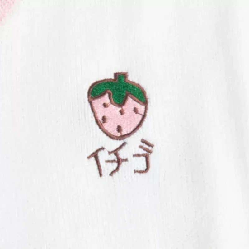 White vest with a cute embroidered strawberry on the top right, adding a sweet and playful touch.