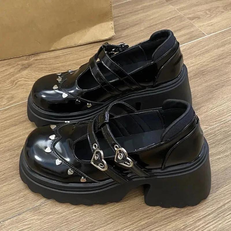 Lateral view of the black Mary Jane shoes with platform, highlighting the two buckles and heart-shaped fastenings, adding a charming and unique touch to the design