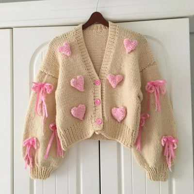 Short beige hand-knitted cardigan with pink hearts and bows