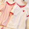 Tee in white with a small red heart, adding a cute and subtle touch to your outfit.